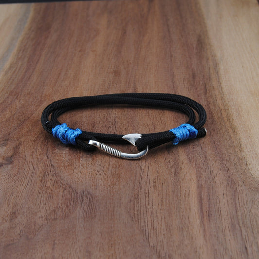 Black bracelet with blue accents and a silver hook clasp on a wooden surface