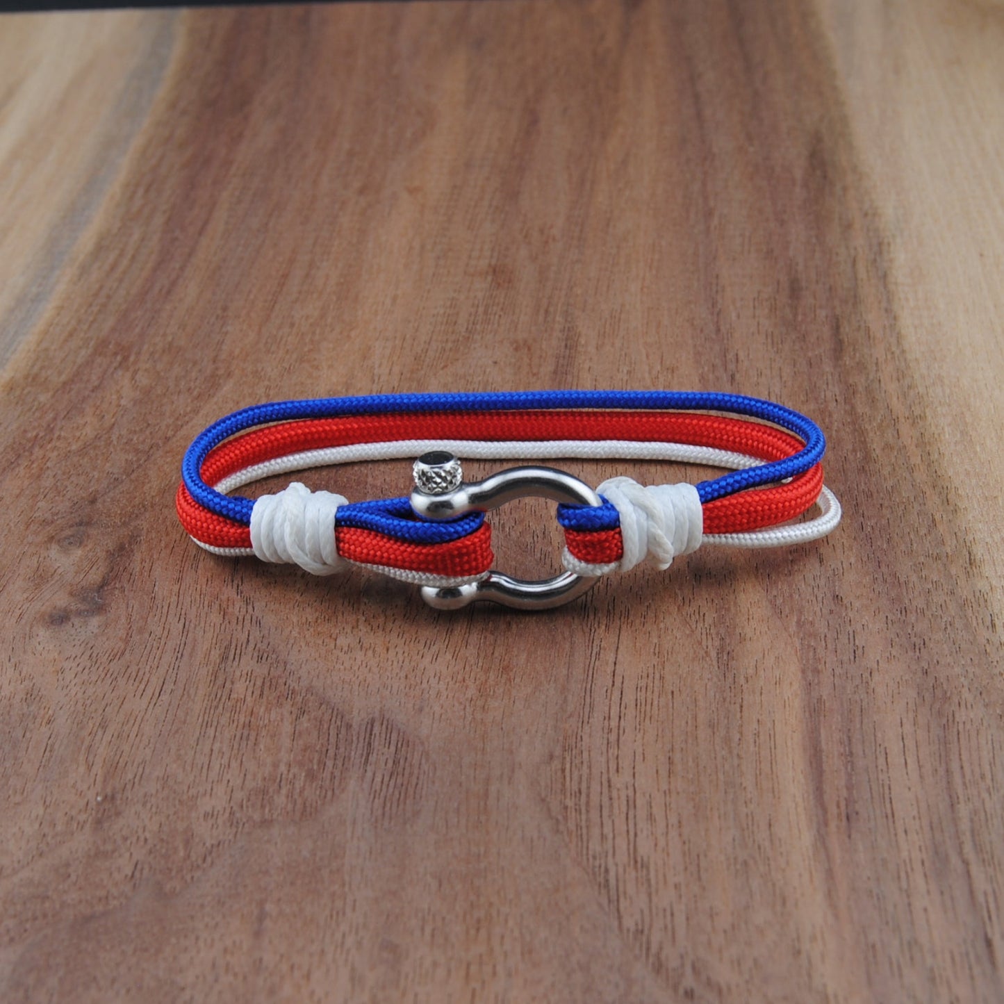 Bracelet with red, white, and blue straps on a wooden surface