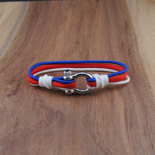 Bracelet with red, white, and blue straps on a wooden surface