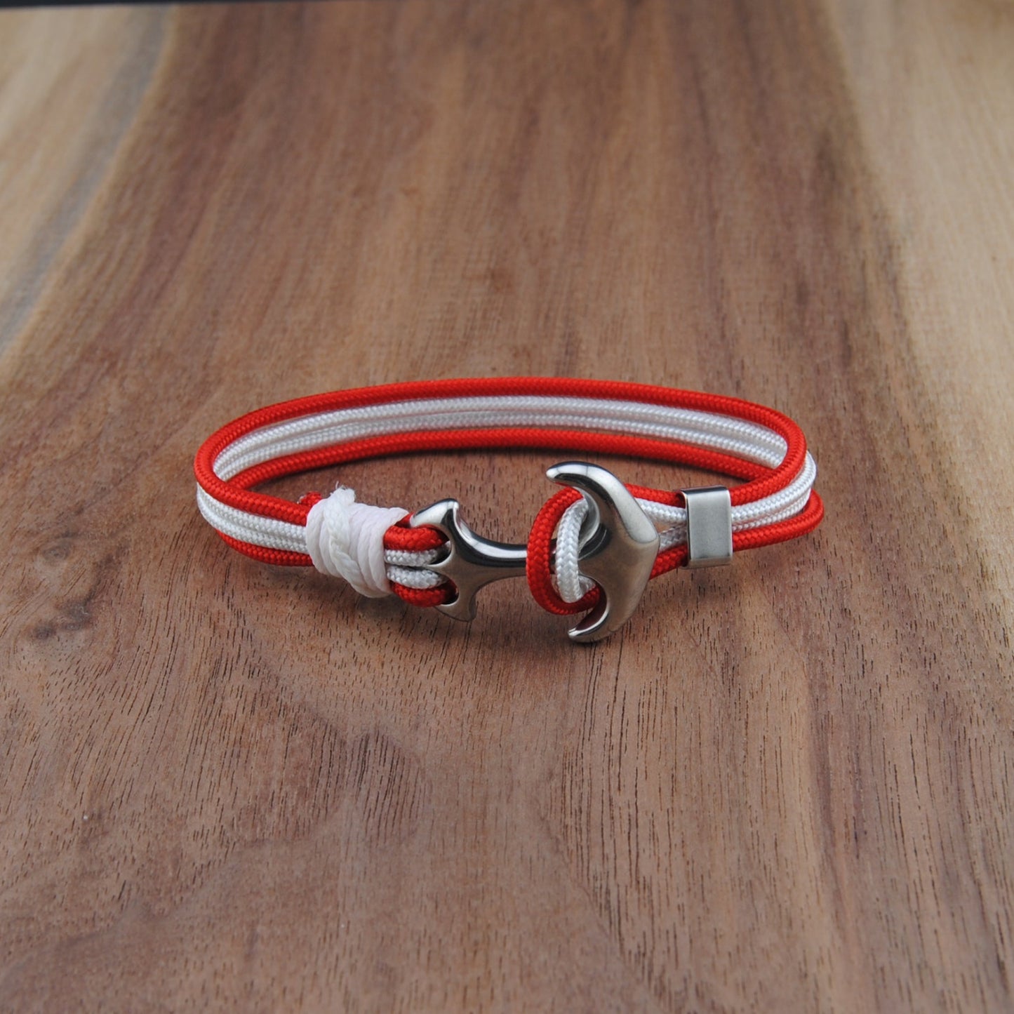 Bracelet with red and white straps on a wooden surface
