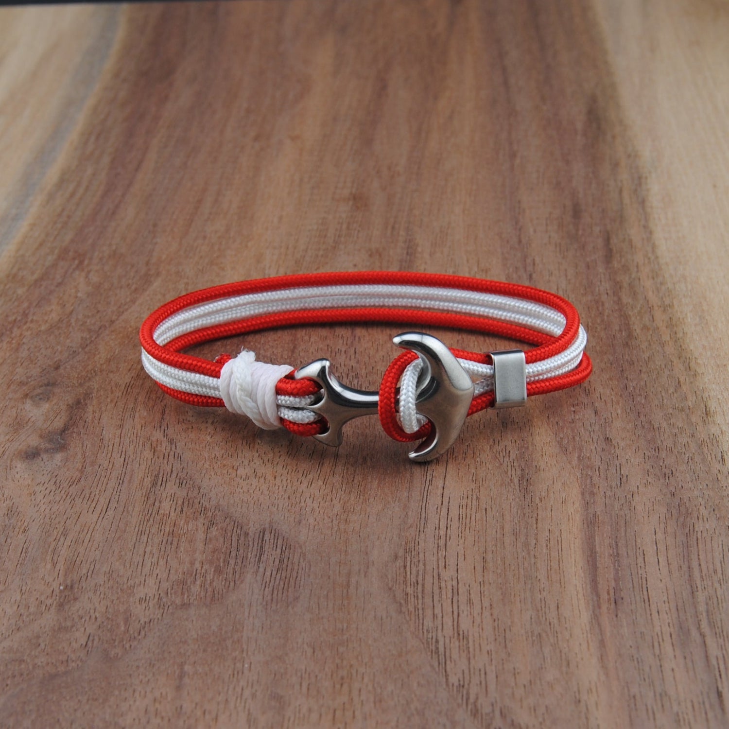 Bracelet with red and white straps on a wooden surface