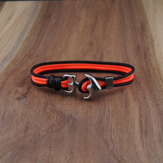 Bracelet with orange and black straps on a wooden surface