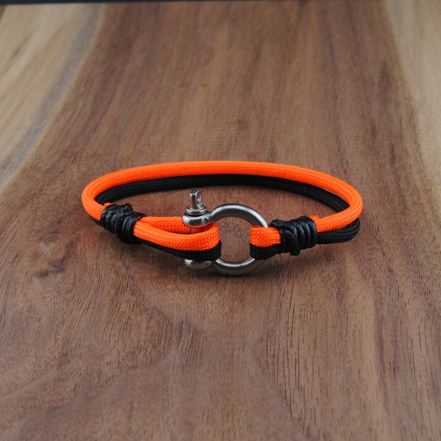Neon orange and black bracelet on a wooden surface