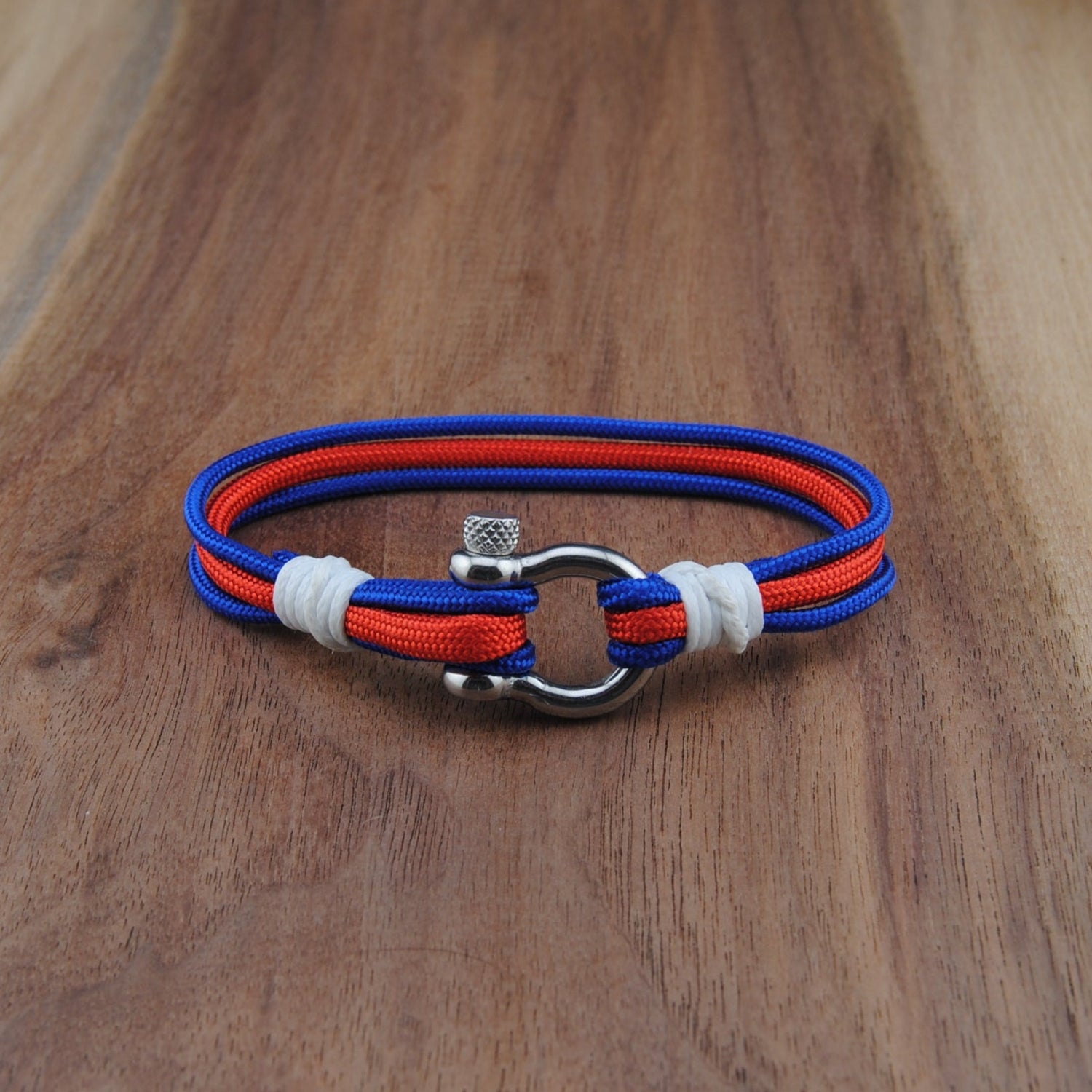 Bracelet with red, blue, and white straps on a wooden surface