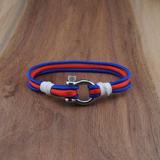 Bracelet with red, blue, and white straps on a wooden surface
