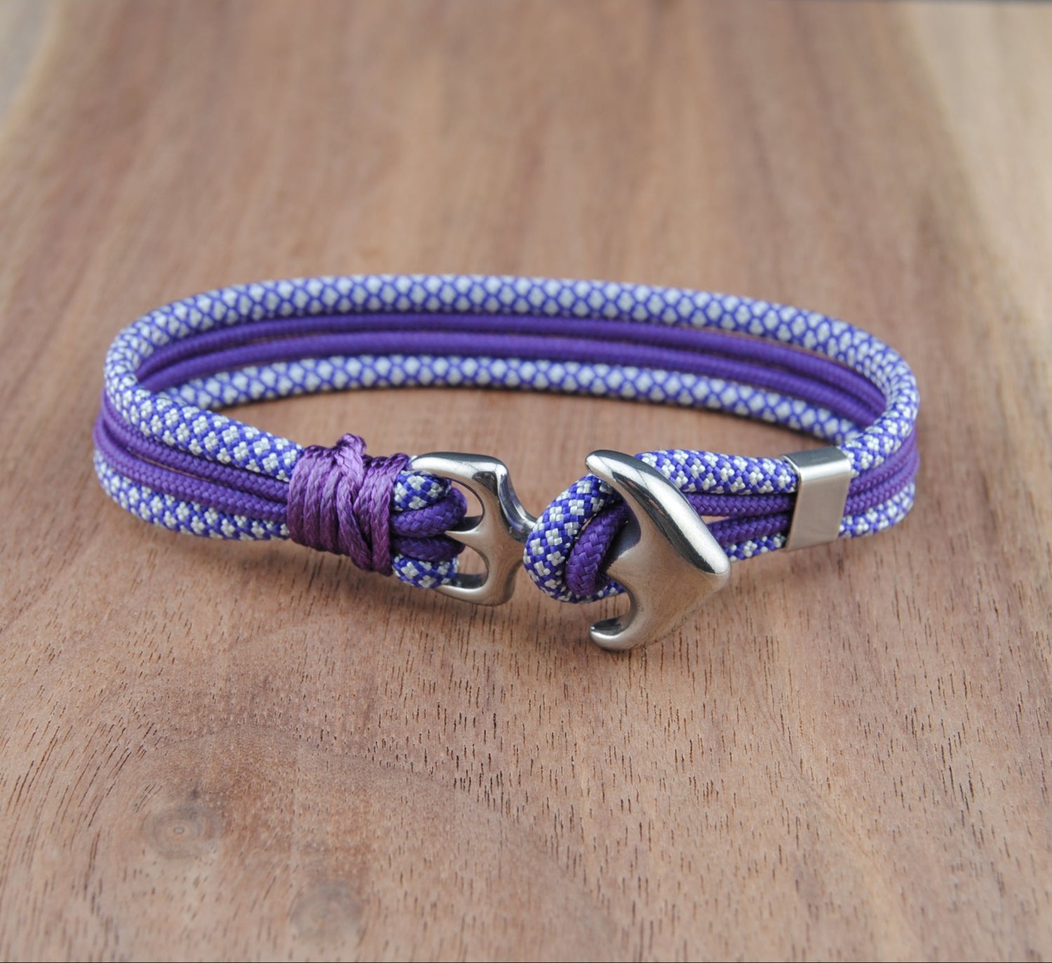 Purple and white braided bracelet with metal clasp on a wooden surface