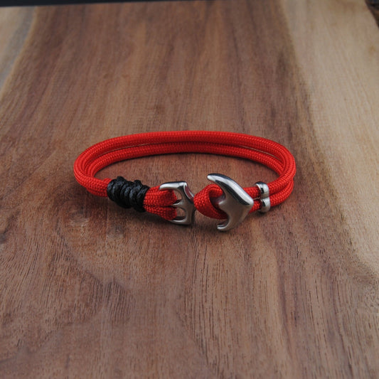Red and black braided bracelet with metal clasp on a wooden surface
