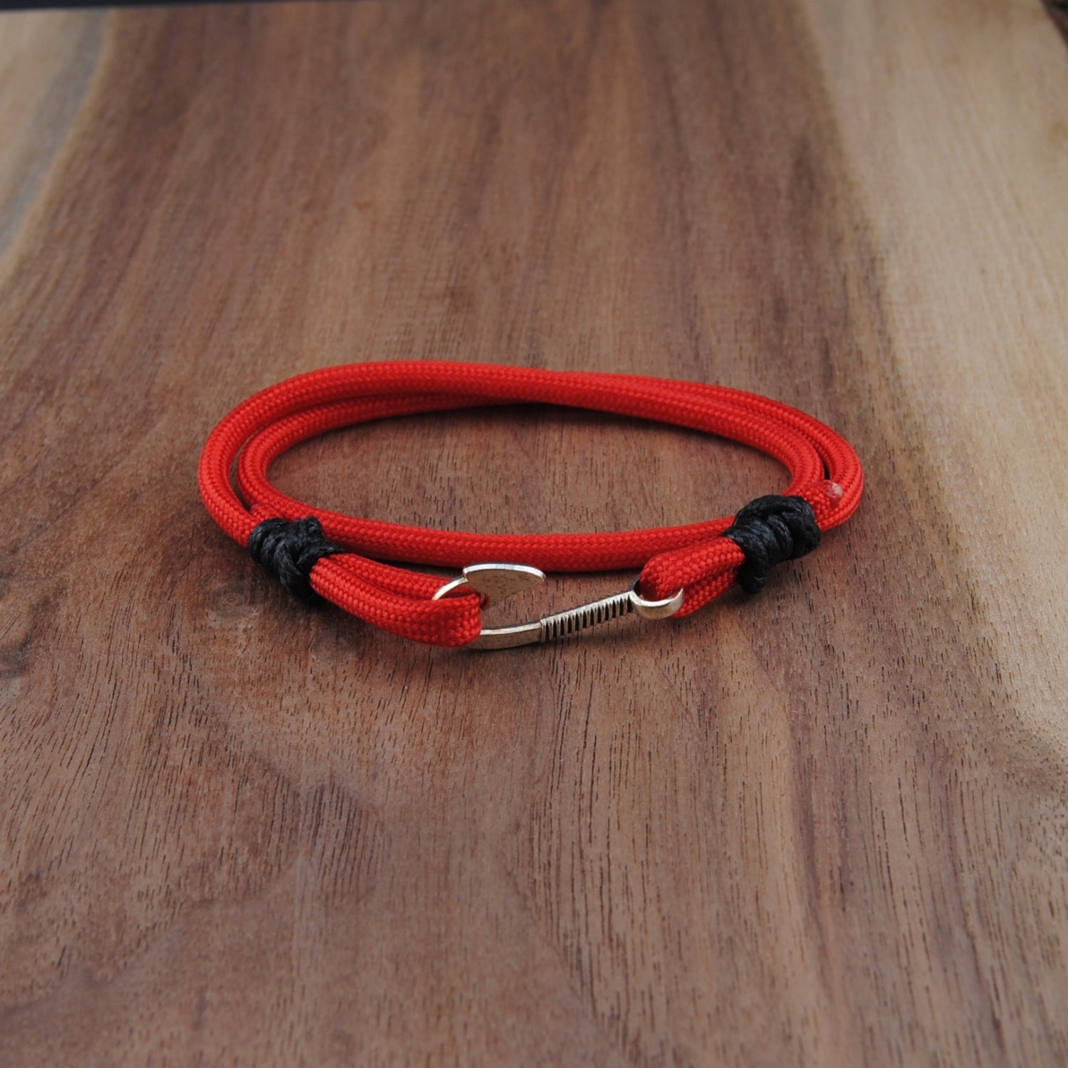 Red and black bracelet with a carabiner on a wooden surface
