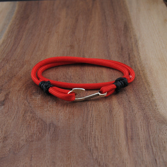 Red and black bracelet with a carabiner on a wooden surface