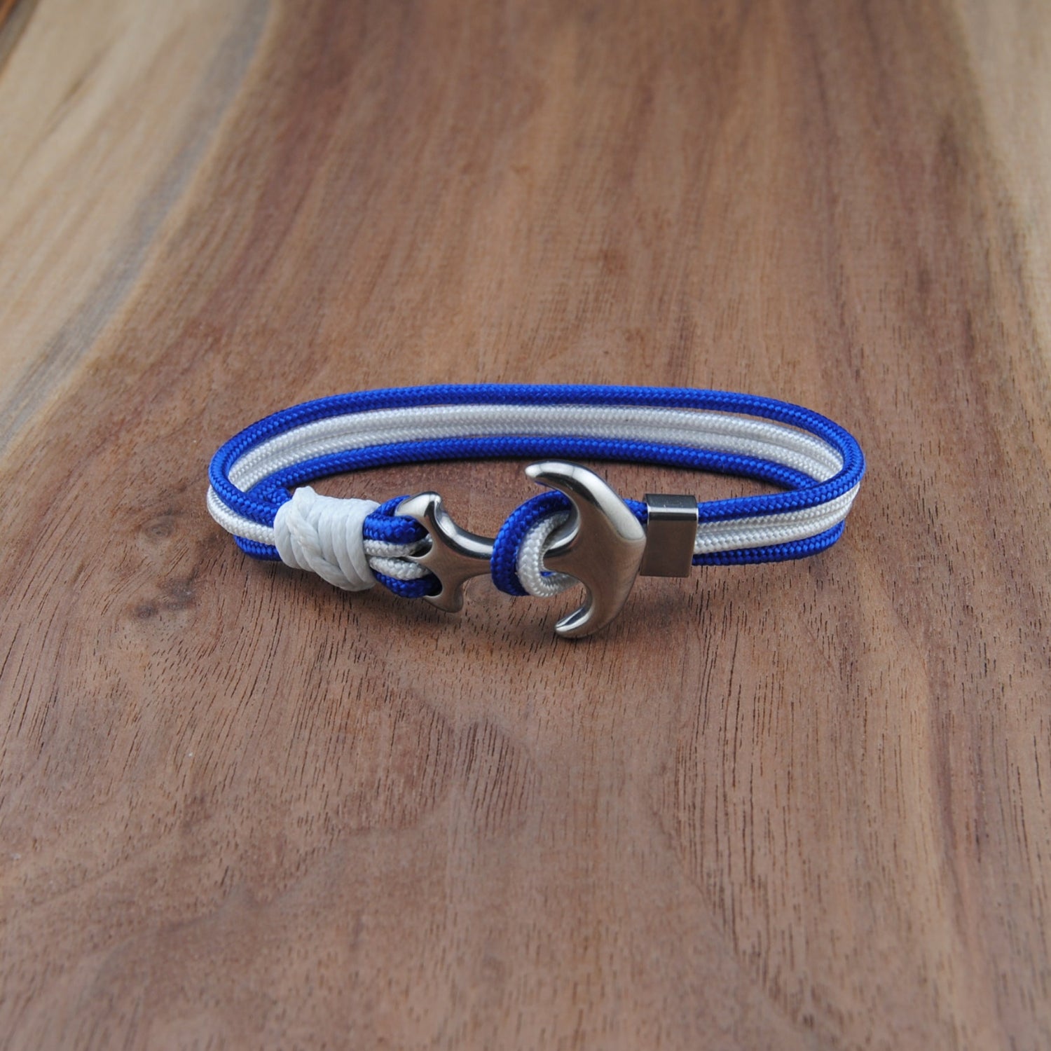 Bracelet with blue and white straps and a silver clasp on a wooden surface