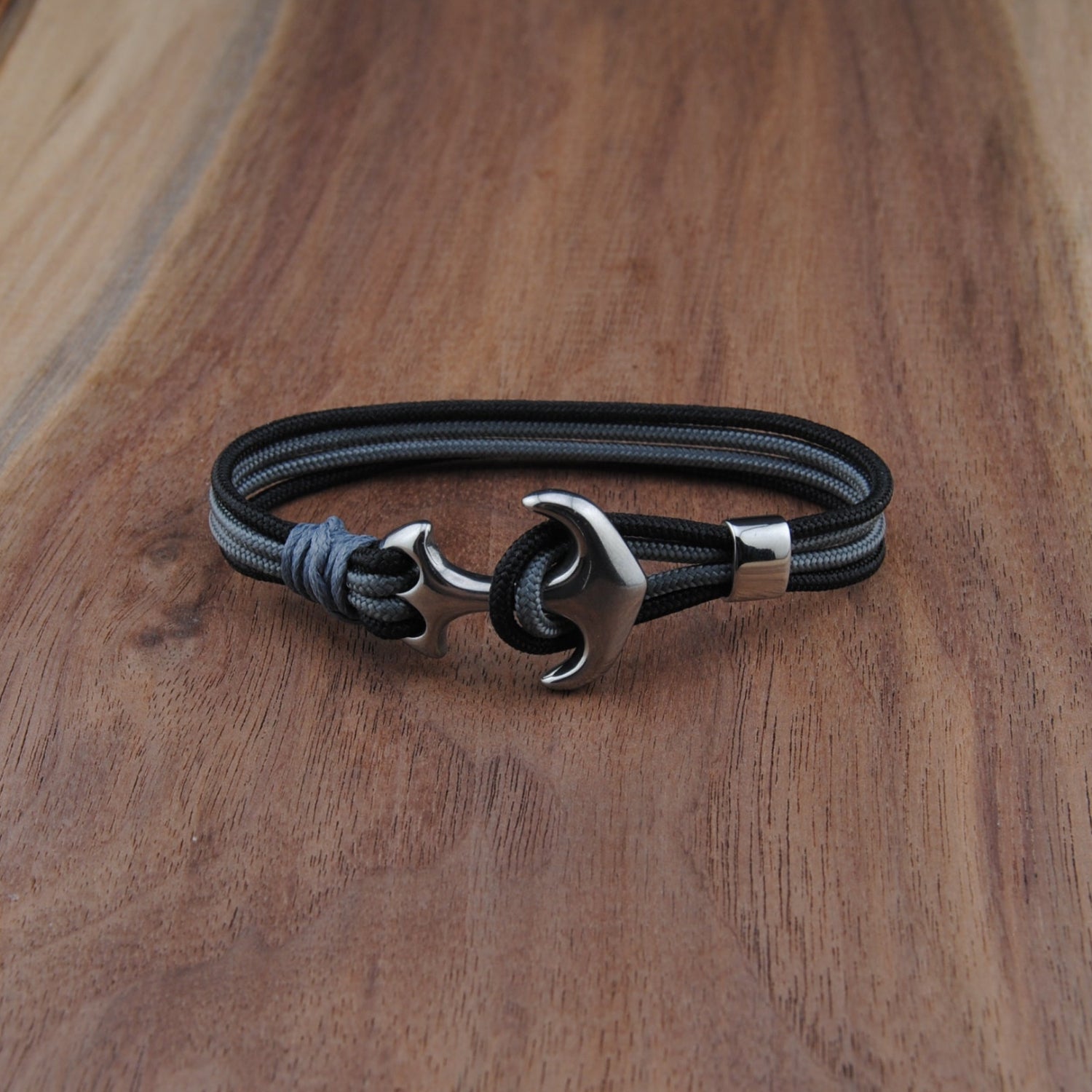 Black and charboal bracelet with a silver clasp on a wooden surface
