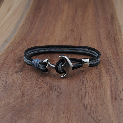 Black and charboal bracelet with a silver clasp on a wooden surface