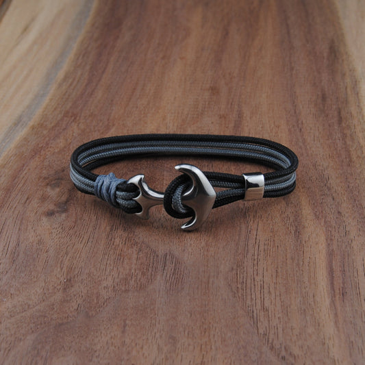 Black and charboal bracelet with a silver clasp on a wooden surface