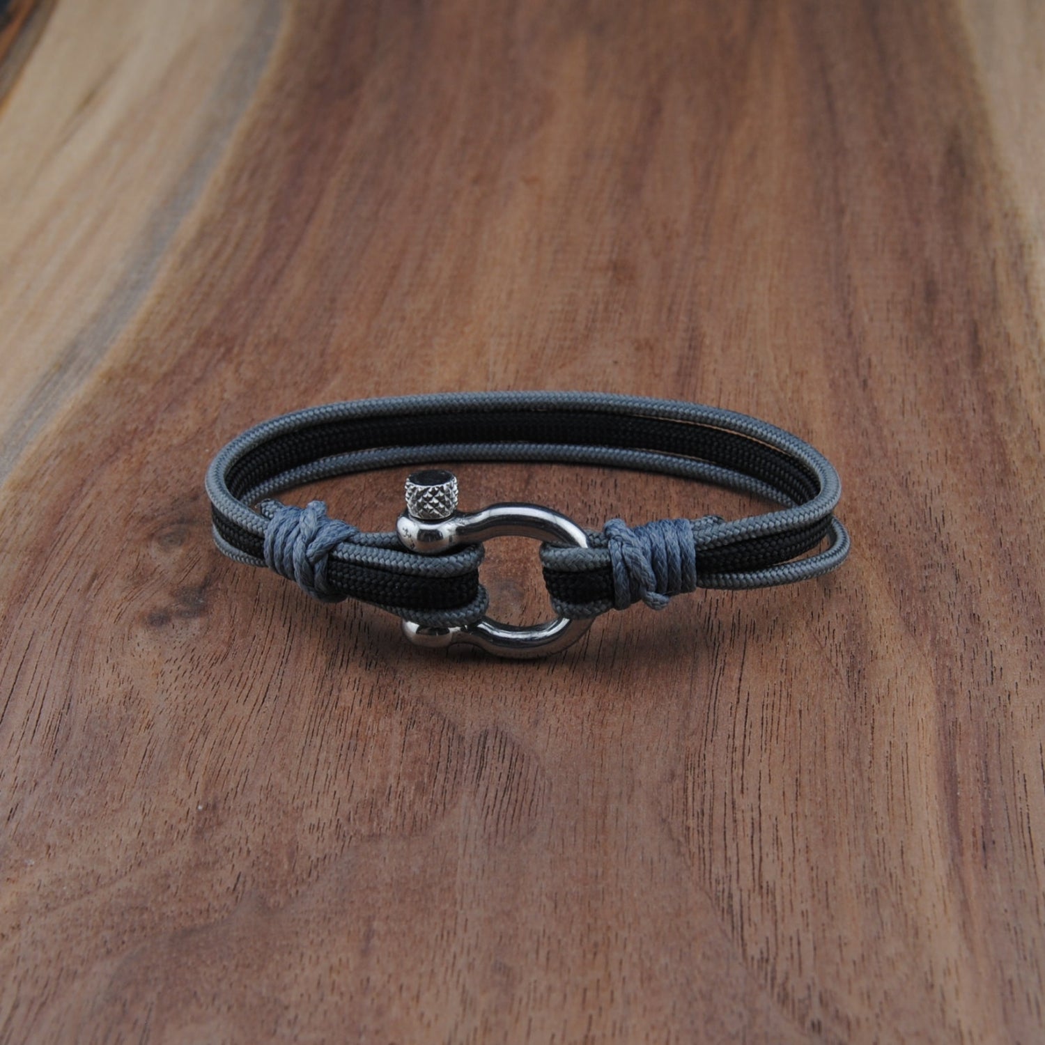 Black and charcoal bracelet with a silver clasp on a wooden surface