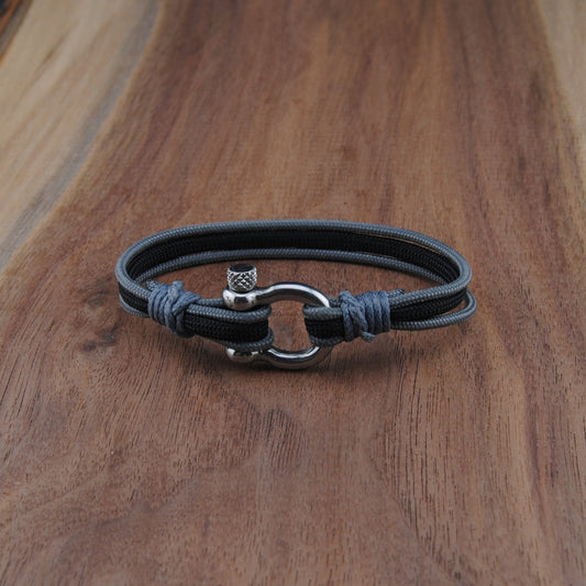 Black and charcoal bracelet with a silver clasp on a wooden surface