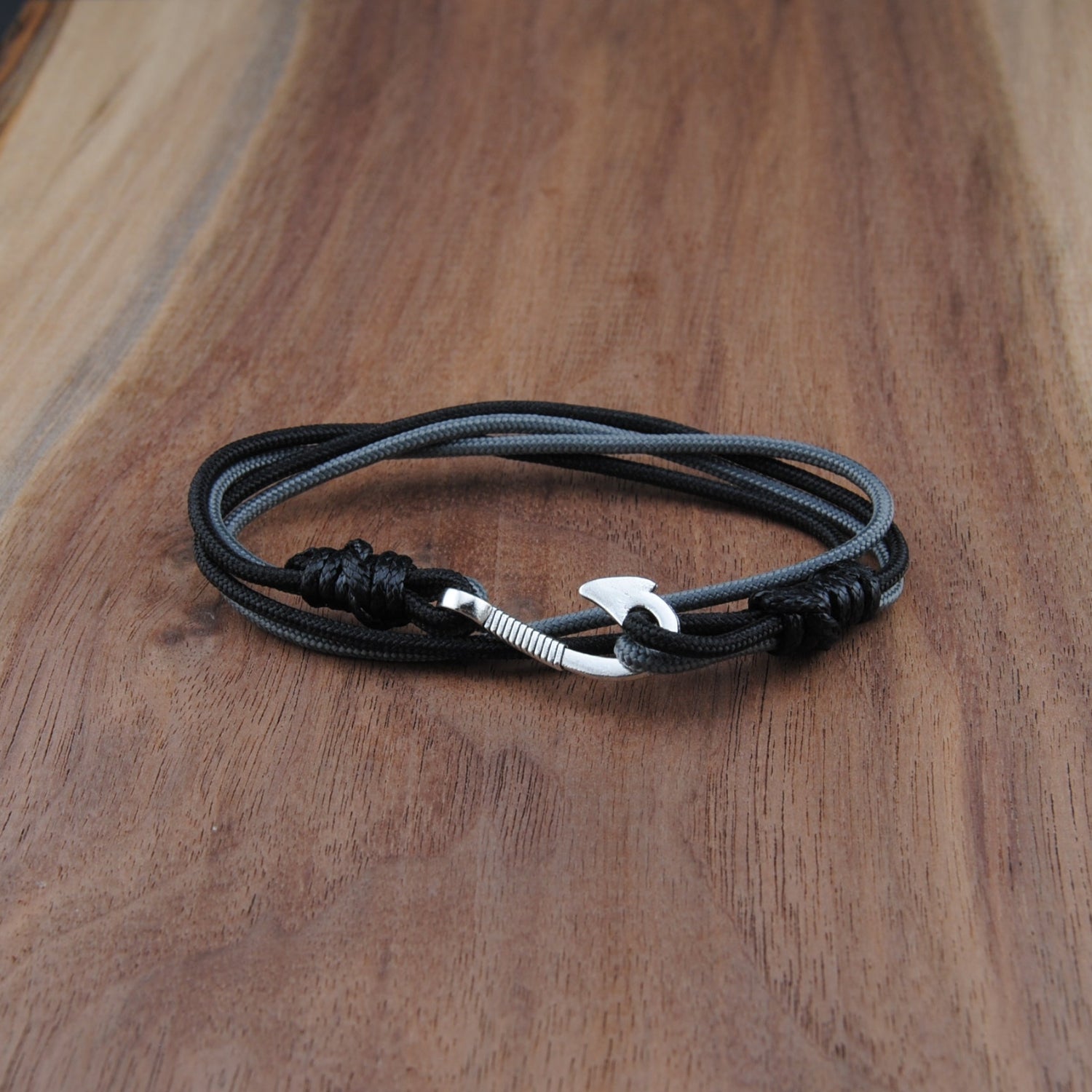 Black and charcoal bracelet with a silver clasp on a wooden surface