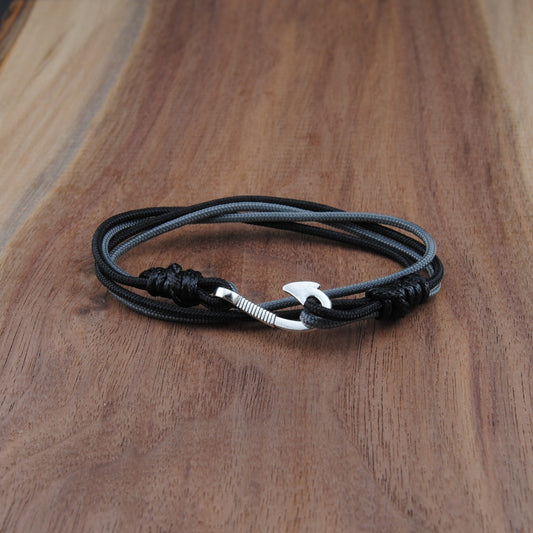 Black and charcoal bracelet with a silver clasp on a wooden surface
