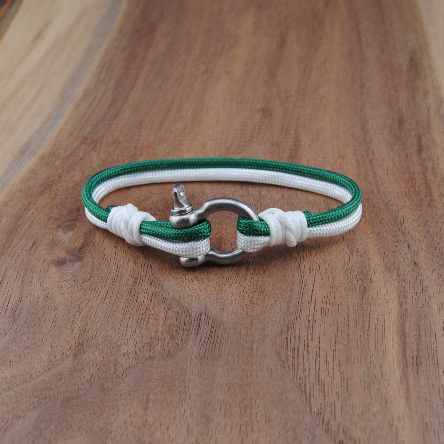 Green and white bracelet with a silver clasp on a wooden surface