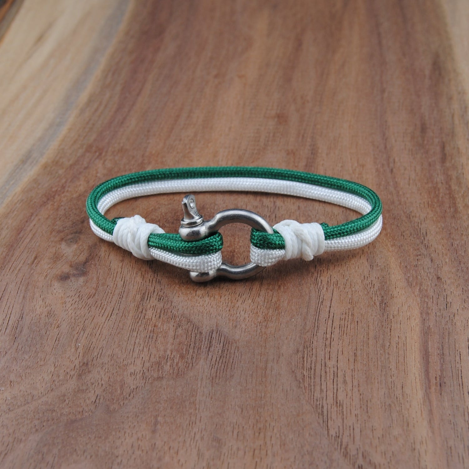 Green and white bracelet with a silver clasp on a wooden surface