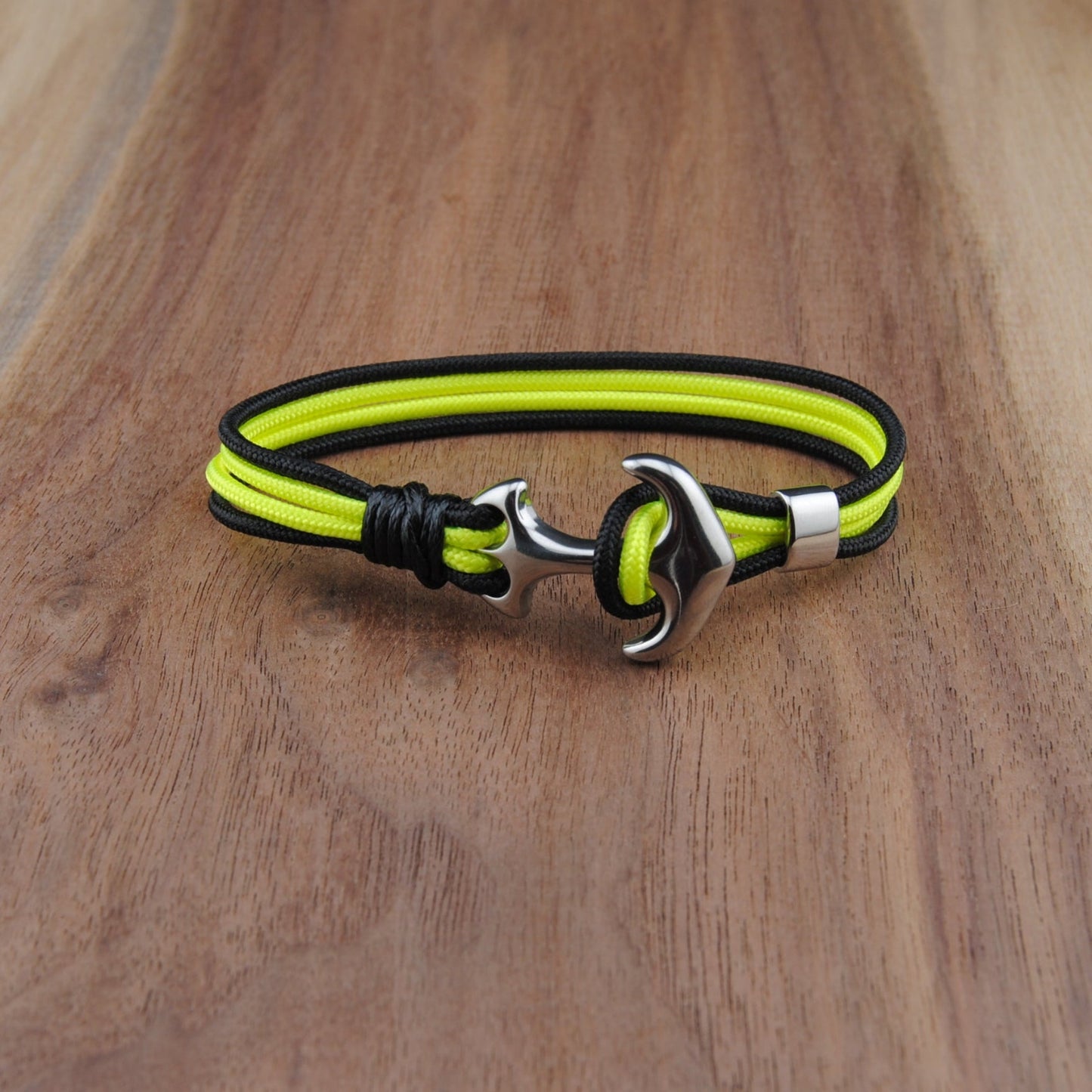 Neon Yellow and black braided bracelet with a silver clasp on a wooden surface