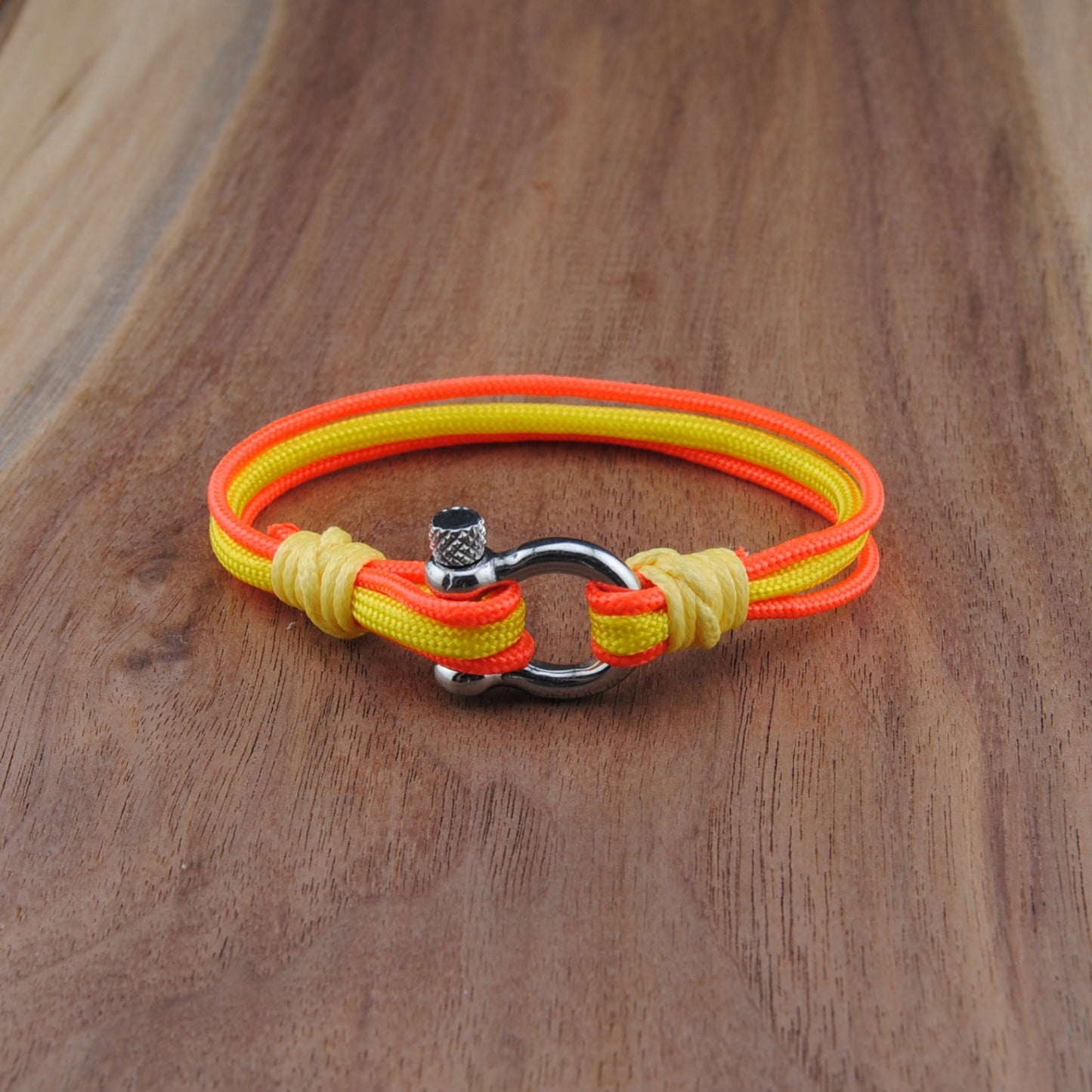 Neon orange and yellow bracelet with a metal clasp on a wooden surface