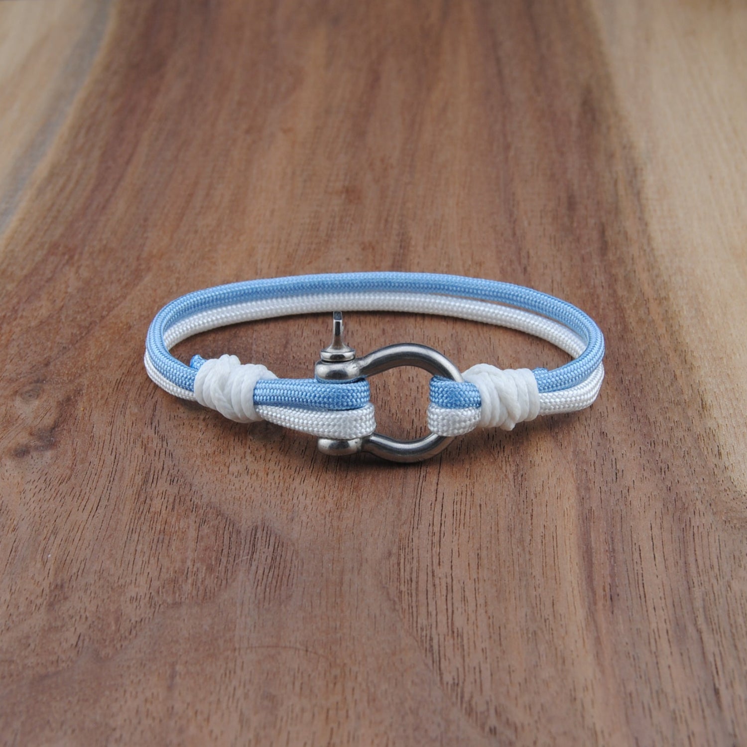 Blue and white braided bracelet with a metal clasp on a wooden surface