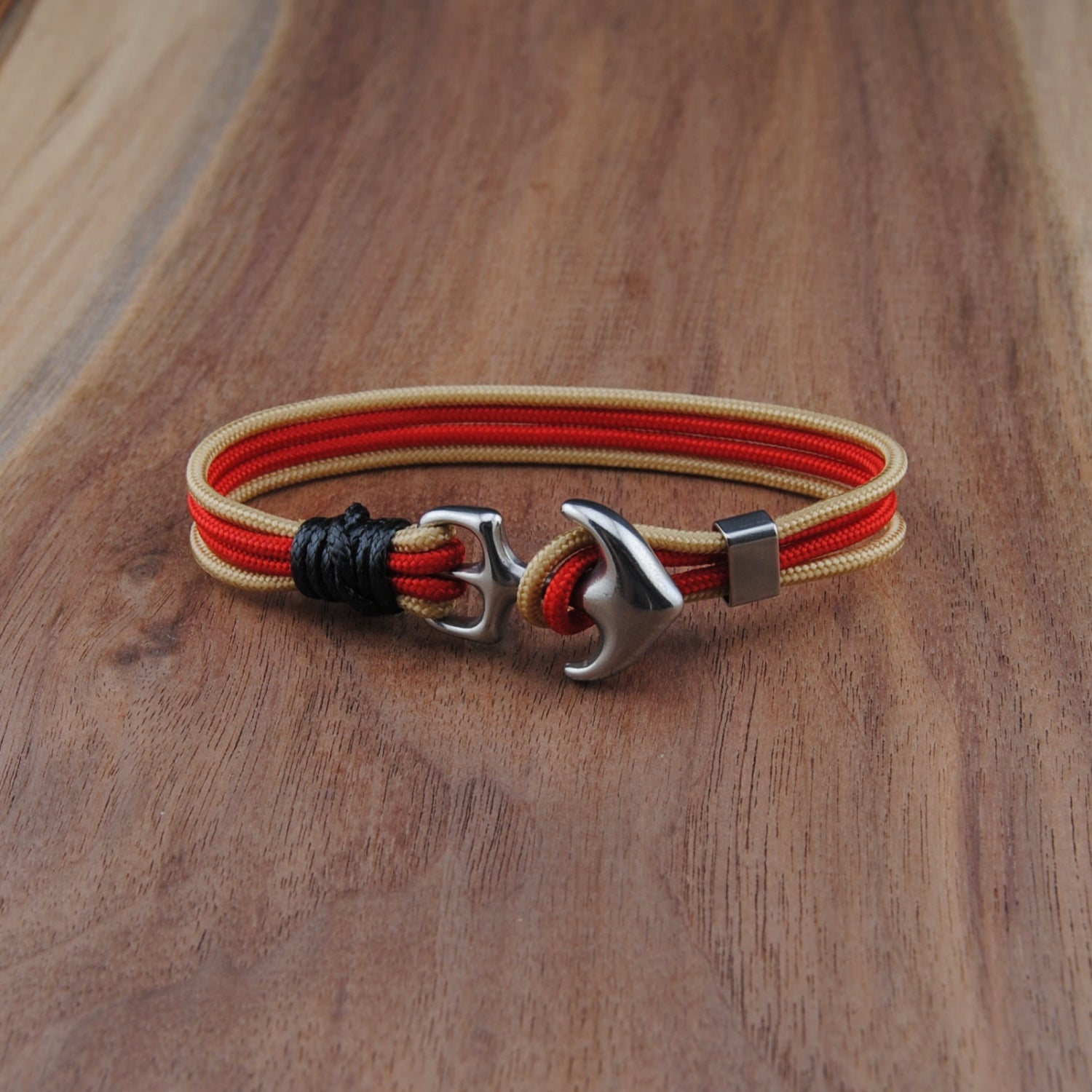 Bracelet with red and gold cords on a wooden surface