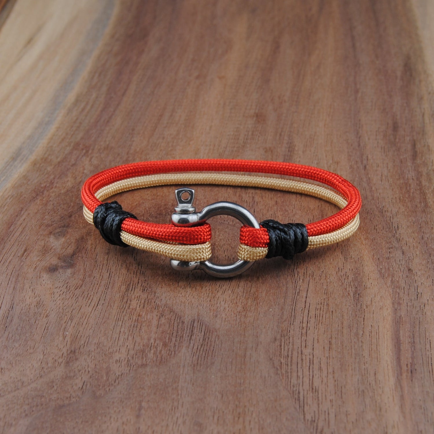 Bracelet with red, and Gold cord on a wooden surface