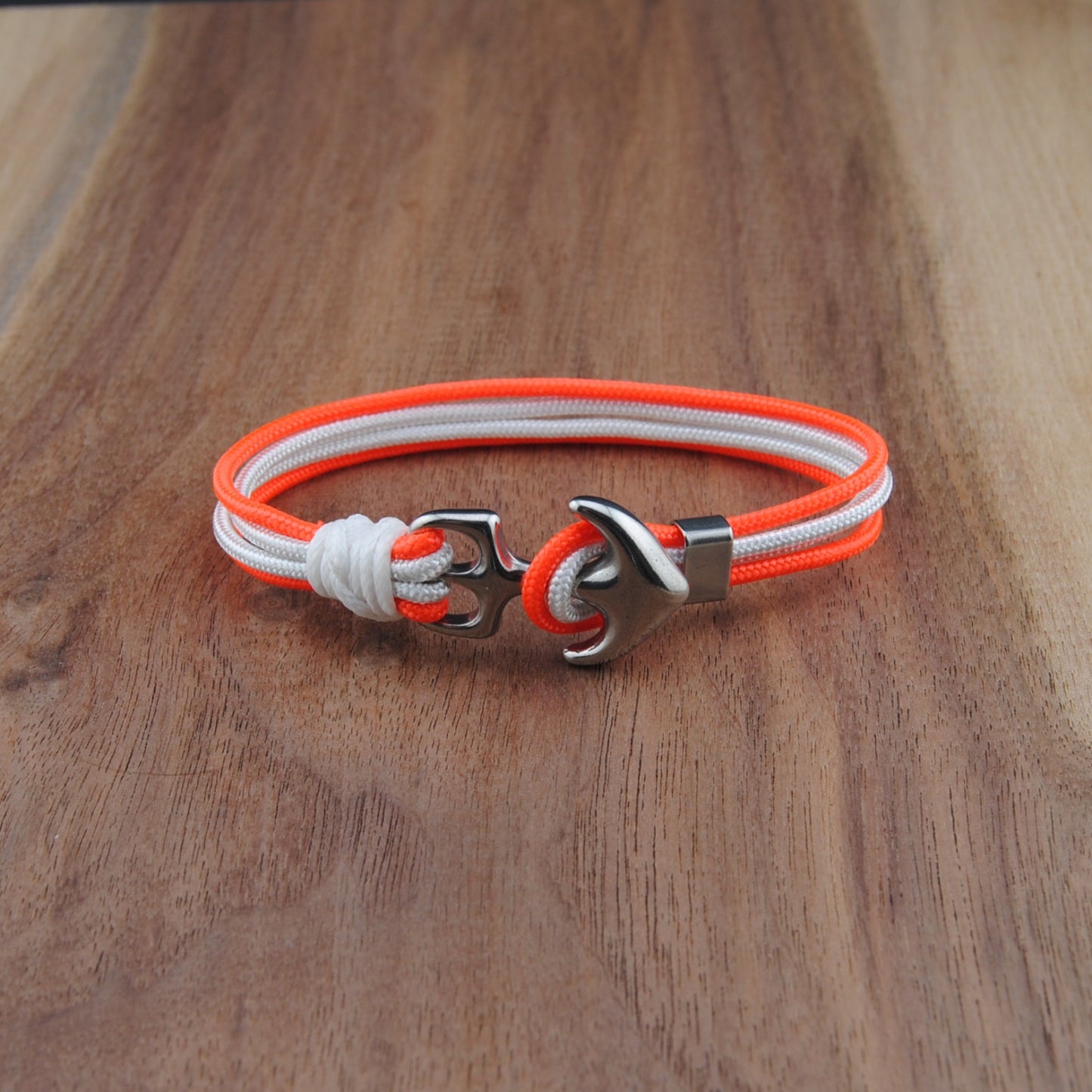 Neon orange and white bracelet with a silver clasp on a wooden surface
