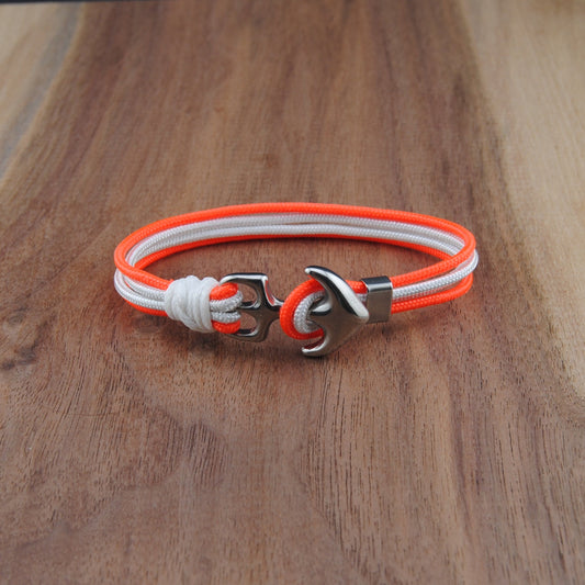 Neon orange and white bracelet with a silver clasp on a wooden surface