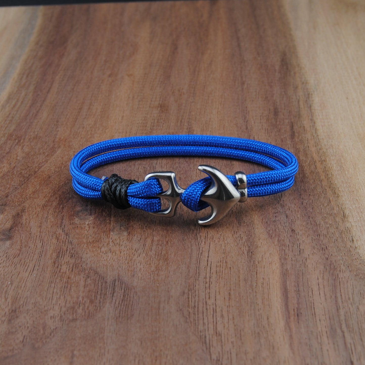 Blue braided bracelet with a silver clasp on a wooden surface