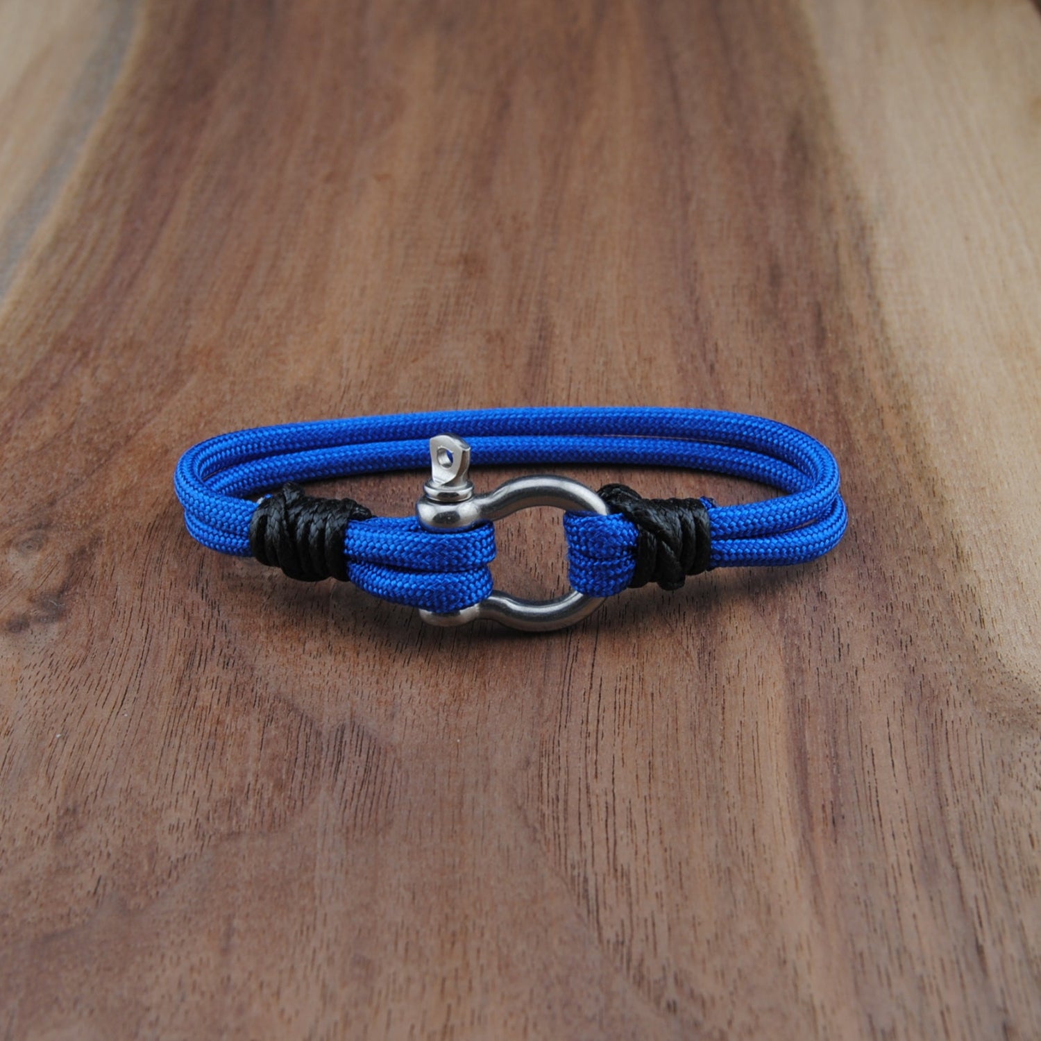 Blue braided bracelet with a silver clasp on a wooden surface
