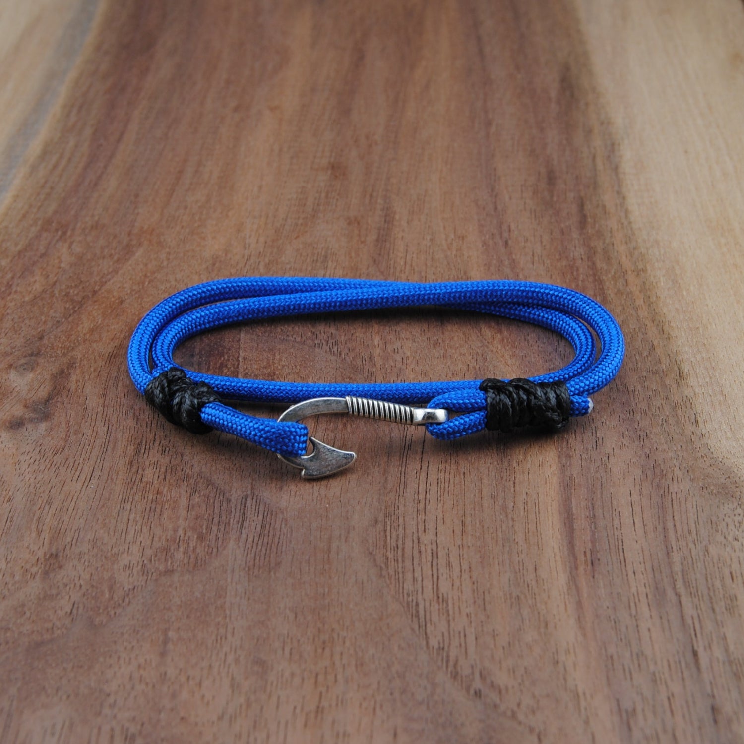 Blue braided bracelet with a metal clasp on a wooden surface