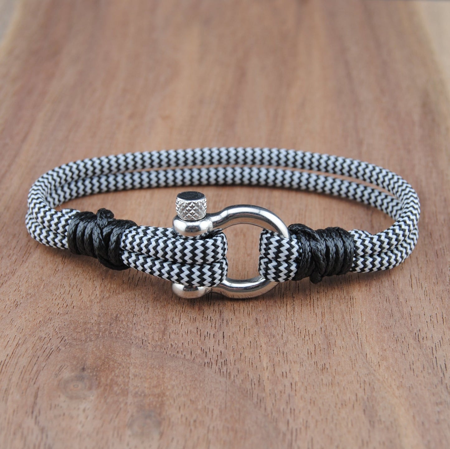 Nautical-style bracelet with black and white pattern on a wooden surface