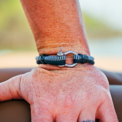 Hand wearing a bracelet with a hook clasp on a blurred natural background